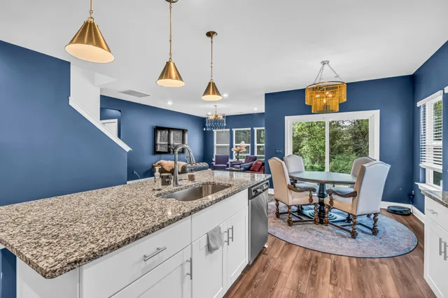 a kitchen with a stove a sink a dining table and chairs with wooden floor