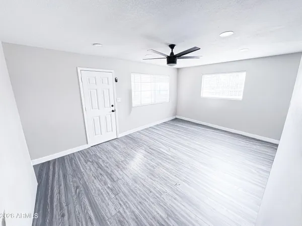 a view of empty room with wooden floor and fan