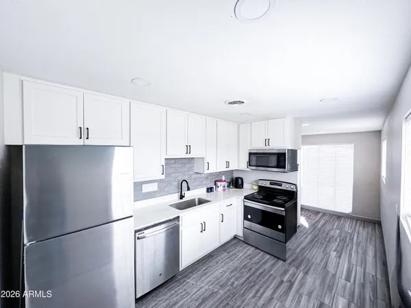 a kitchen with a refrigerator a stove top oven and white cabinets