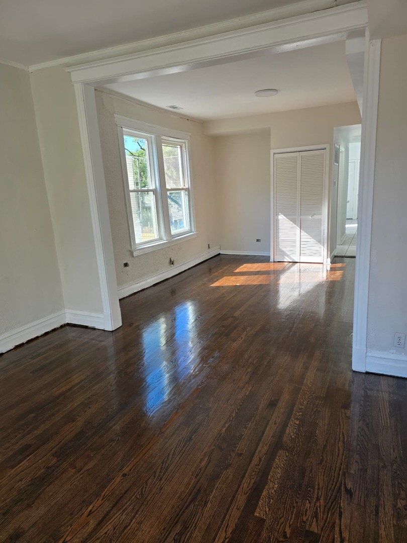 5740 South Elizabeth Street Chicago, IL 60636 - Photo 5 of 45 a view of an empty room with wooden floor and a window