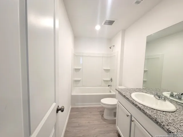 a bathroom with a granite countertop sink toilet mirror and shower