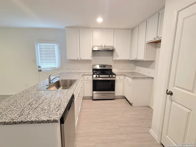 a kitchen with granite countertop kitchen island stainless steel appliances a stove sink and cabinets