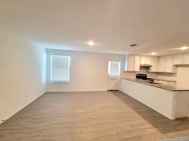 a living room with stainless steel appliances kitchen island sink refrigerator and window