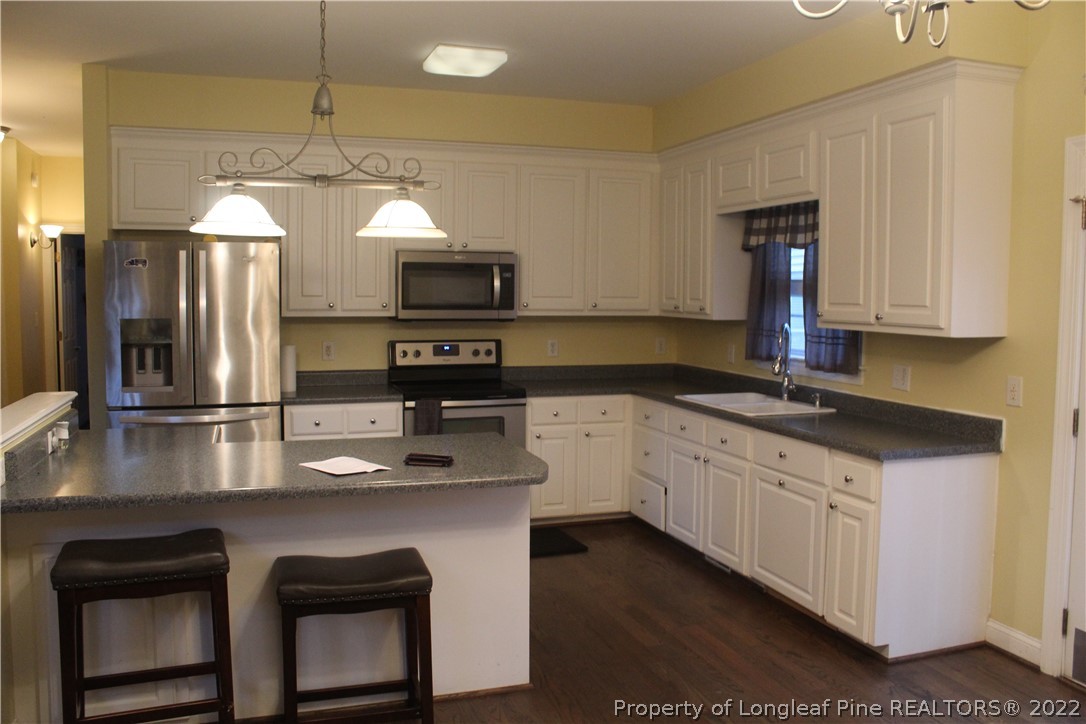 678 Tilghman Road Coats, NC 27521 - Photo 29 of 47 a kitchen with kitchen island granite countertop a sink cabinets and stainless steel appliances