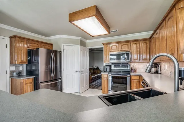 a kitchen with stainless steel appliances granite countertop a refrigerator a stove and a sink with large window