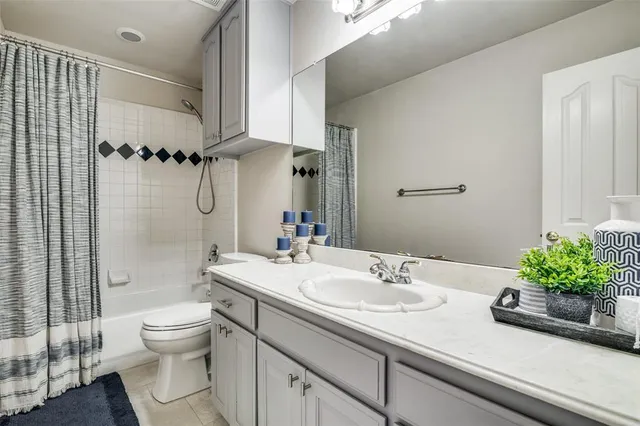 a bathroom with a granite countertop sink a toilet a mirror and shower