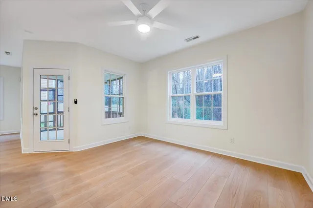 a view of an empty room with a window and wooden floor