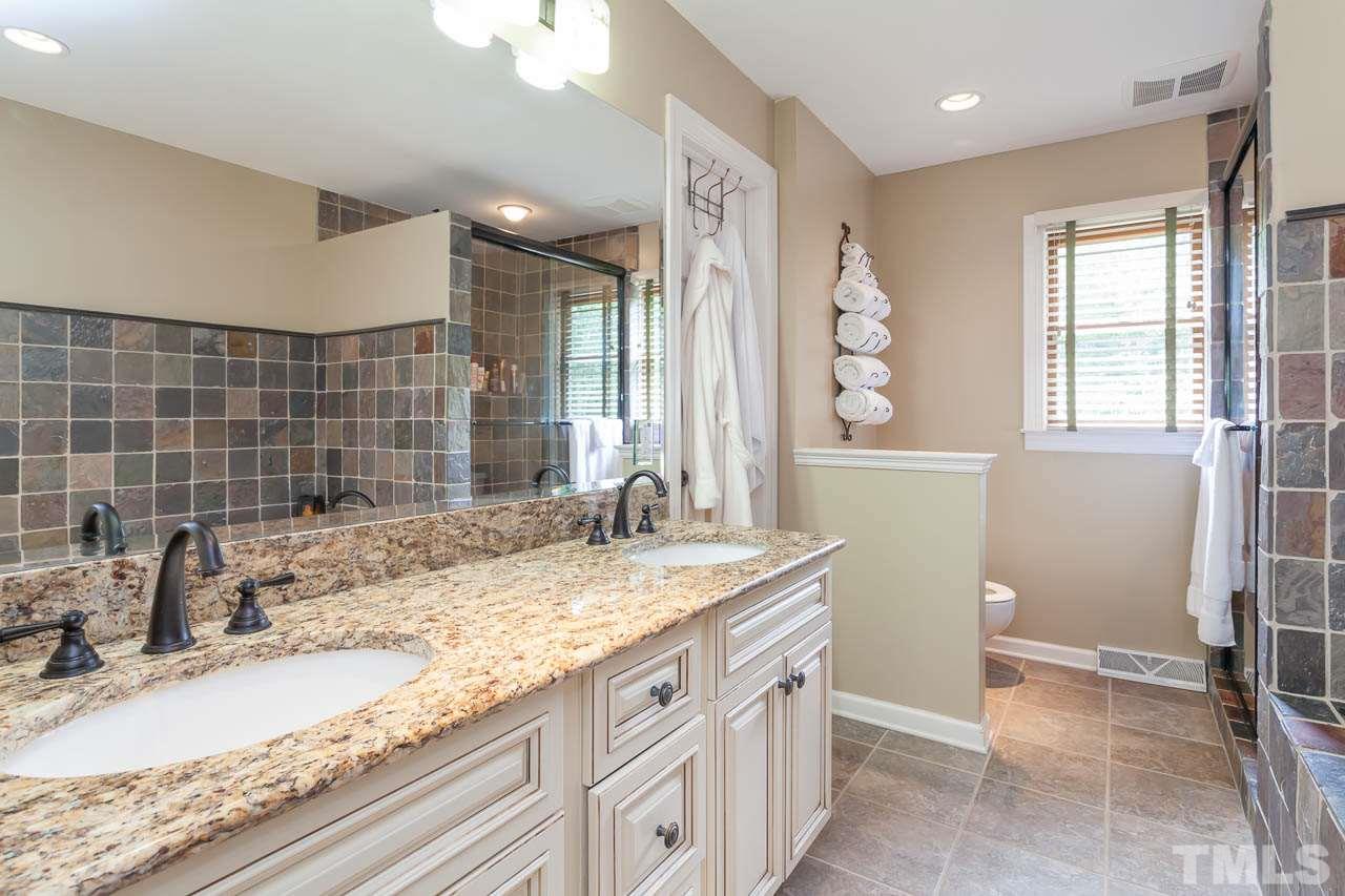 7317 Ridge Grove Court Raleigh, NC 27615 - Photo 12 of 25 a bathroom with a granite countertop sink a mirror and a bathtub