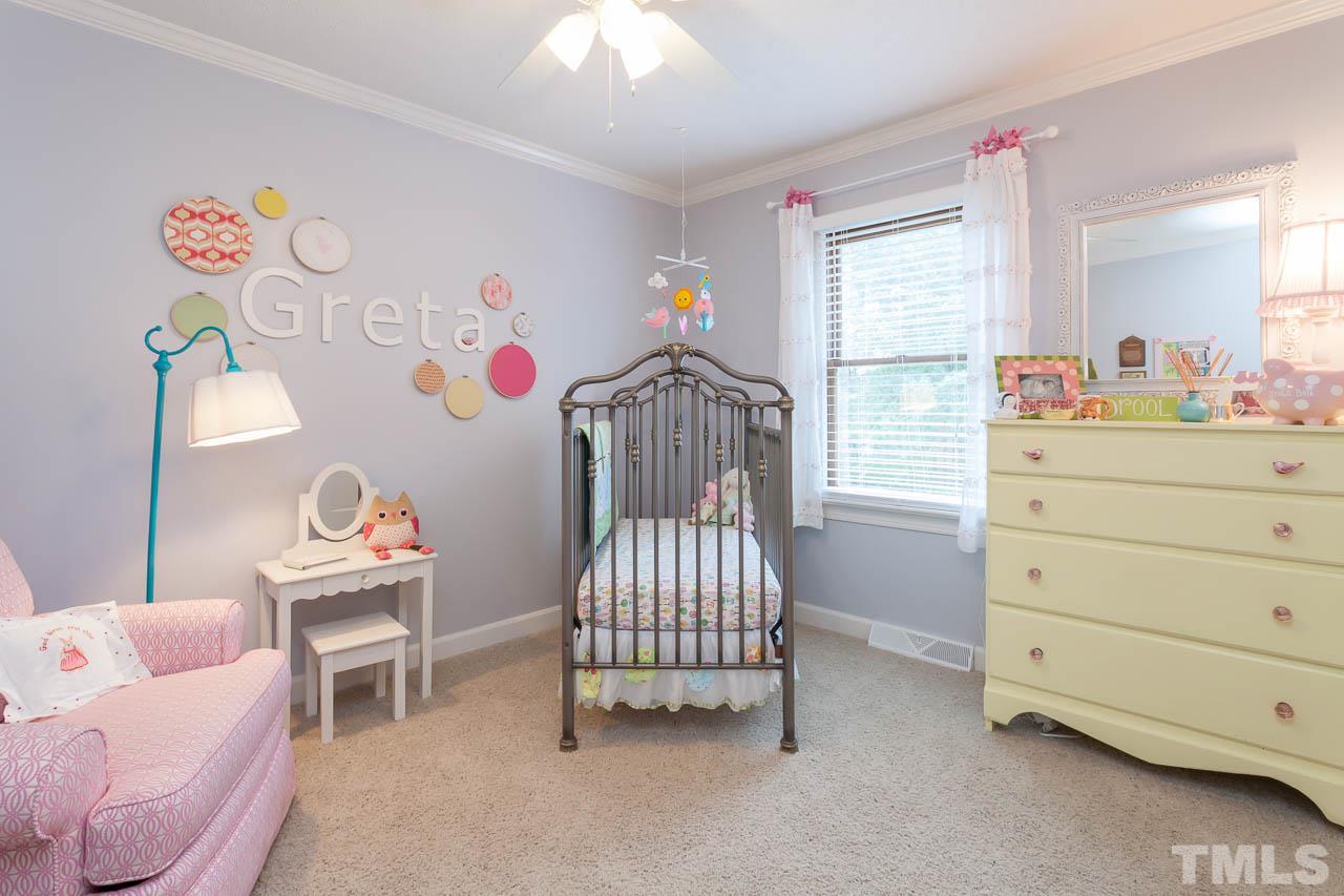 7317 Ridge Grove Court Raleigh, NC 27615 - Photo 8 of 25 a bedroom with a baby bed a couch and a chandelier