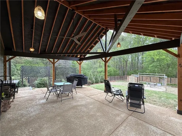 a view of a patio with table and chairs under an umbrella with a barbeque grill