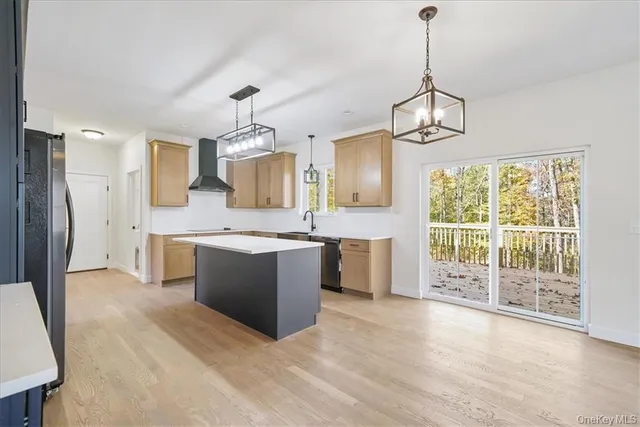 a large kitchen with kitchen island a large counter top a sink stainless steel appliances and cabinets