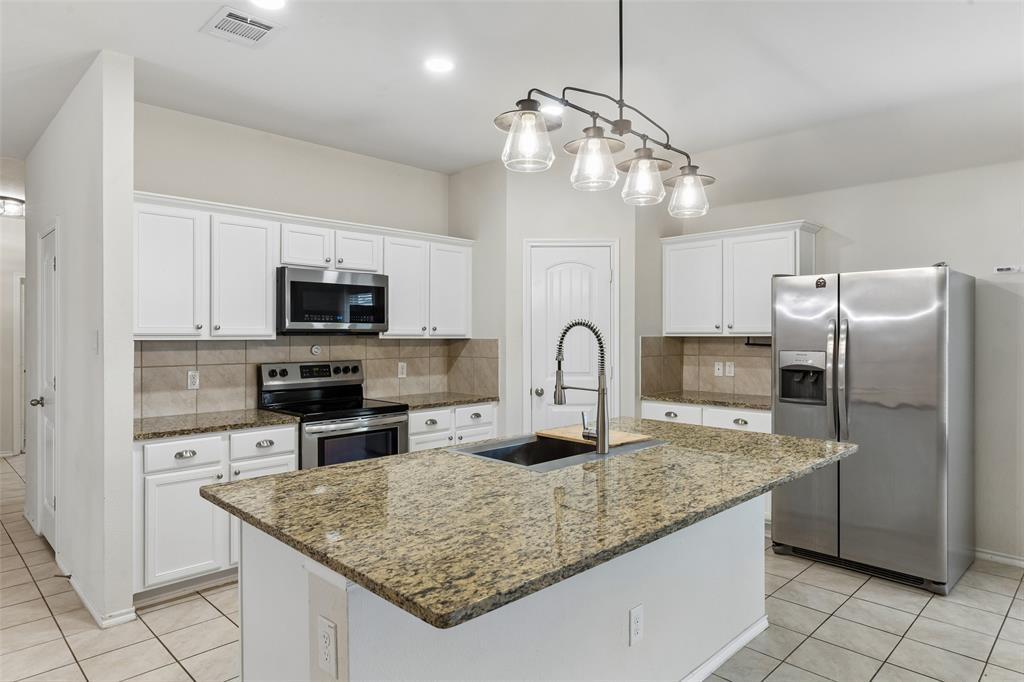 2850 Dusty Road Forney, TX 75126 - Photo 4 of 11 Kitchen featuring a central island with an undermount sink, granite countertops, and white cabinetry