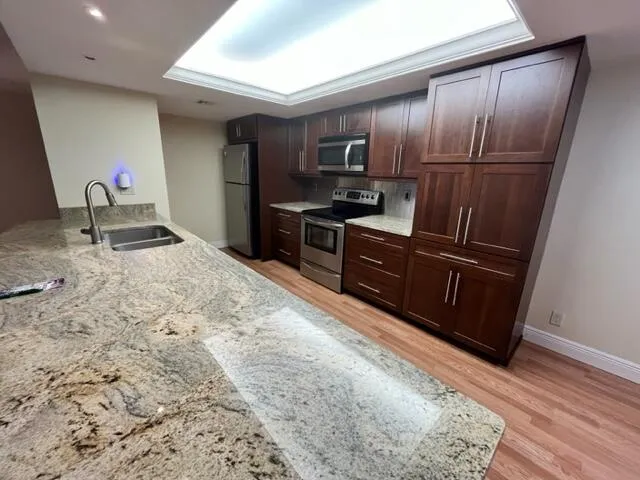 a kitchen with granite countertop wooden cabinets a refrigerator and a sink