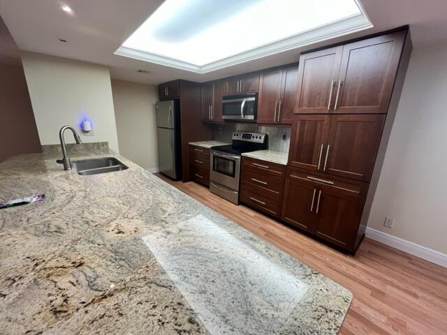 2255 Lindell Boulevard, Unit 4209 Delray Beach, FL 33444 - Photo 2 of 15 a kitchen with granite countertop wooden cabinets a refrigerator and a sink