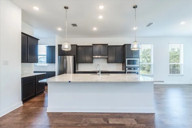 a large kitchen with stainless steel appliances a large counter top a stove and a sink