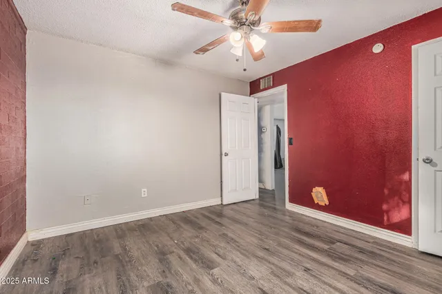 an empty room with wooden floor and fan