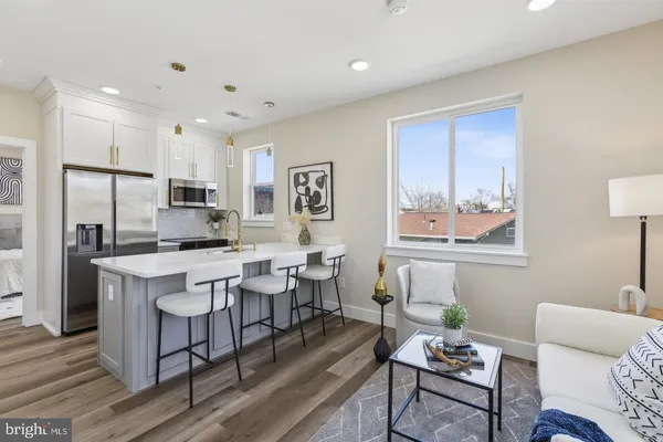 a living room with stainless steel appliances kitchen island granite countertop furniture and a refrigerator