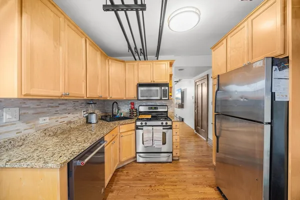 a kitchen with stainless steel appliances granite countertop a refrigerator a sink a stove a washer dryer and a cabinets