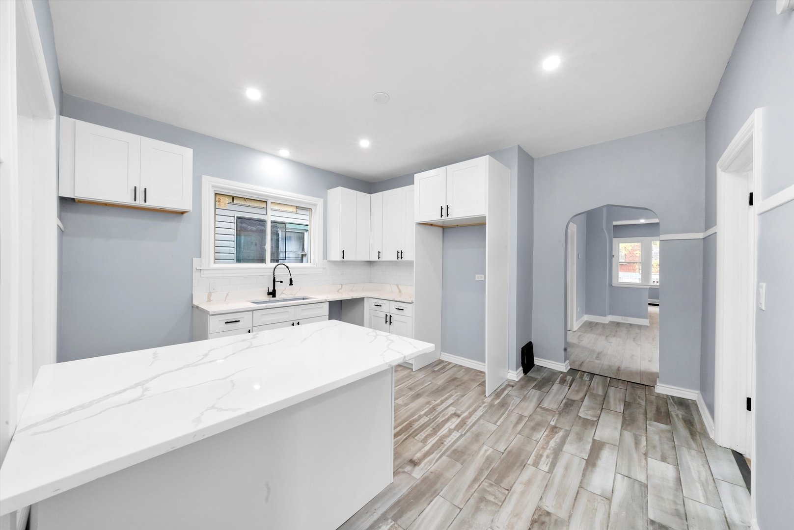 11730 South Perry Avenue Chicago, IL 60628 - Photo 12 of 25 a large white kitchen with wooden floor and cabinetry