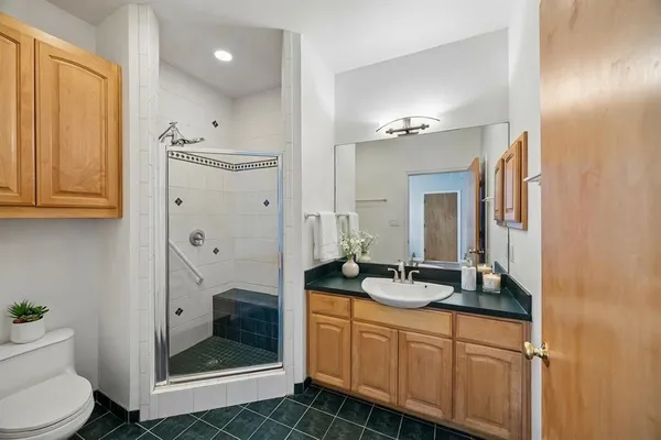 a bathroom with a granite countertop sink a toilet a mirror and shower