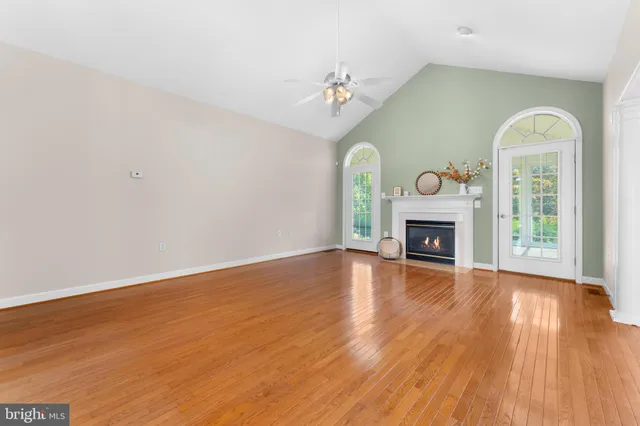 a view of an empty room with wooden floor fireplace and a window