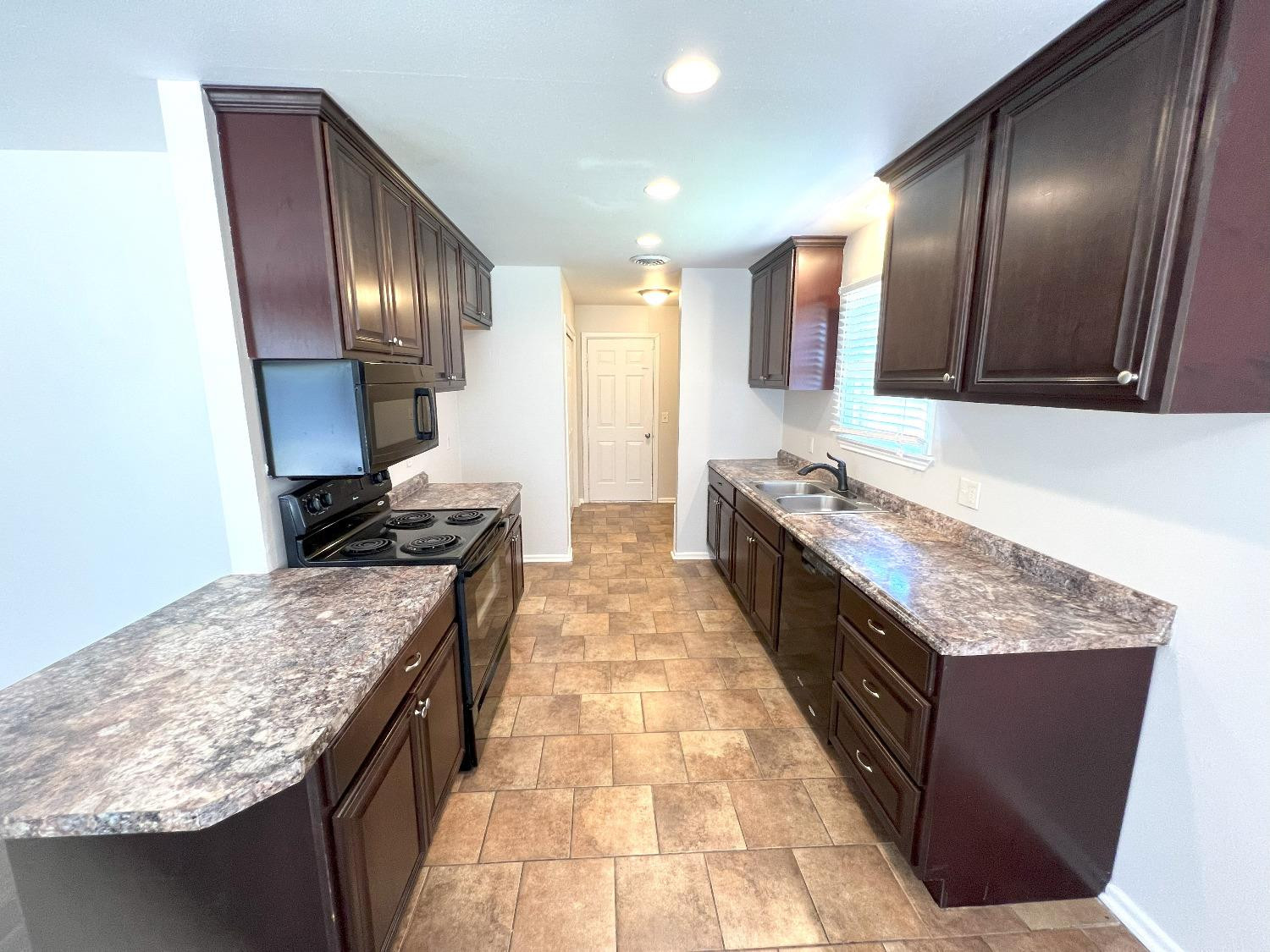 4214 54th Street Lubbock, TX 79413 - Photo 16 of 18 a large kitchen with granite countertop a sink and dishwasher a stove top oven with wooden floor