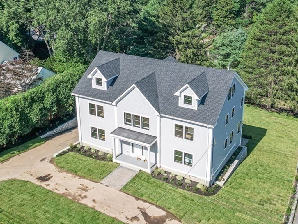 a aerial view of a house with yard and trees in the background