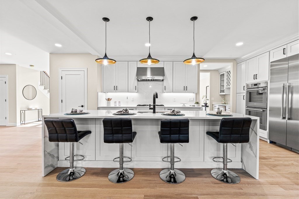 228 Ridge Street Winchester, MA 01890 - Photo 13 of 42 a kitchen with stainless steel appliances kitchen island granite countertop a dining table chairs and white cabinets