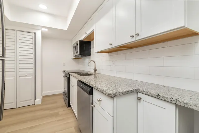 a kitchen with stainless steel appliances granite countertop a sink and a white cabinets