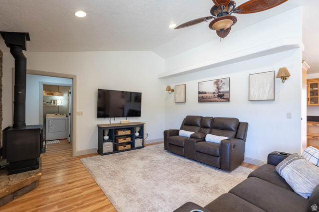 1504 Rome Way Apple Valley, UT 84737 - Photo 3 of 22 Vaulted ceilings with a ceiling fan, wood-finish flooring, recessed lighting, and a wood-burning stove with a stone surround