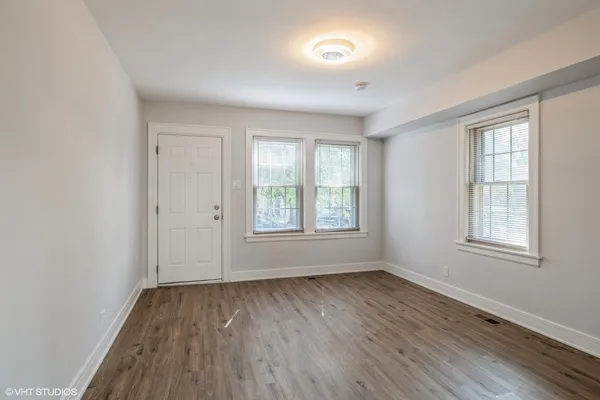 an empty room with wooden floor and windows