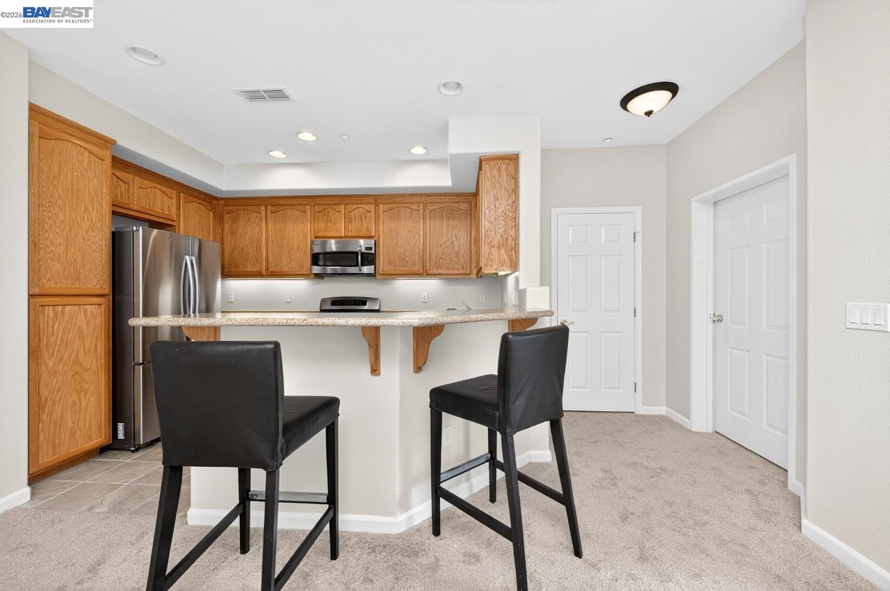3391 Monaghan Street Dublin, CA 94568 - Photo 12 of 57 a kitchen with stainless steel appliances granite countertop a dining table chairs refrigerator and sink