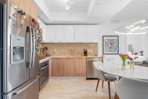 a kitchen with stainless steel appliances white cabinets and wooden floor