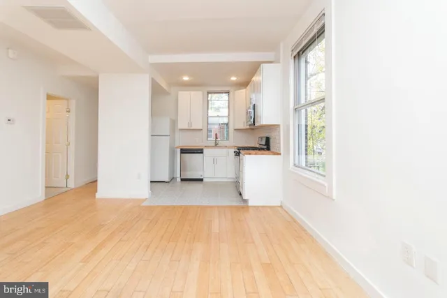 a view of a kitchen with wooden floor and a living room