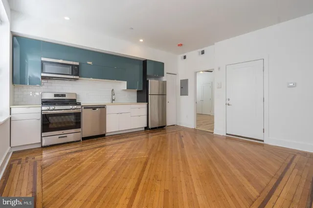 a view of a kitchen with a sink stove cabinets and empty room