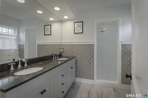 a bathroom with a granite countertop sink a mirror and shower