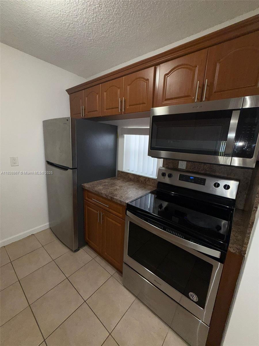 8560 Sherman Circle North, Unit 105 Miramar, FL 33025 - Photo 4 of 14 a kitchen with granite countertop a stove and a microwave