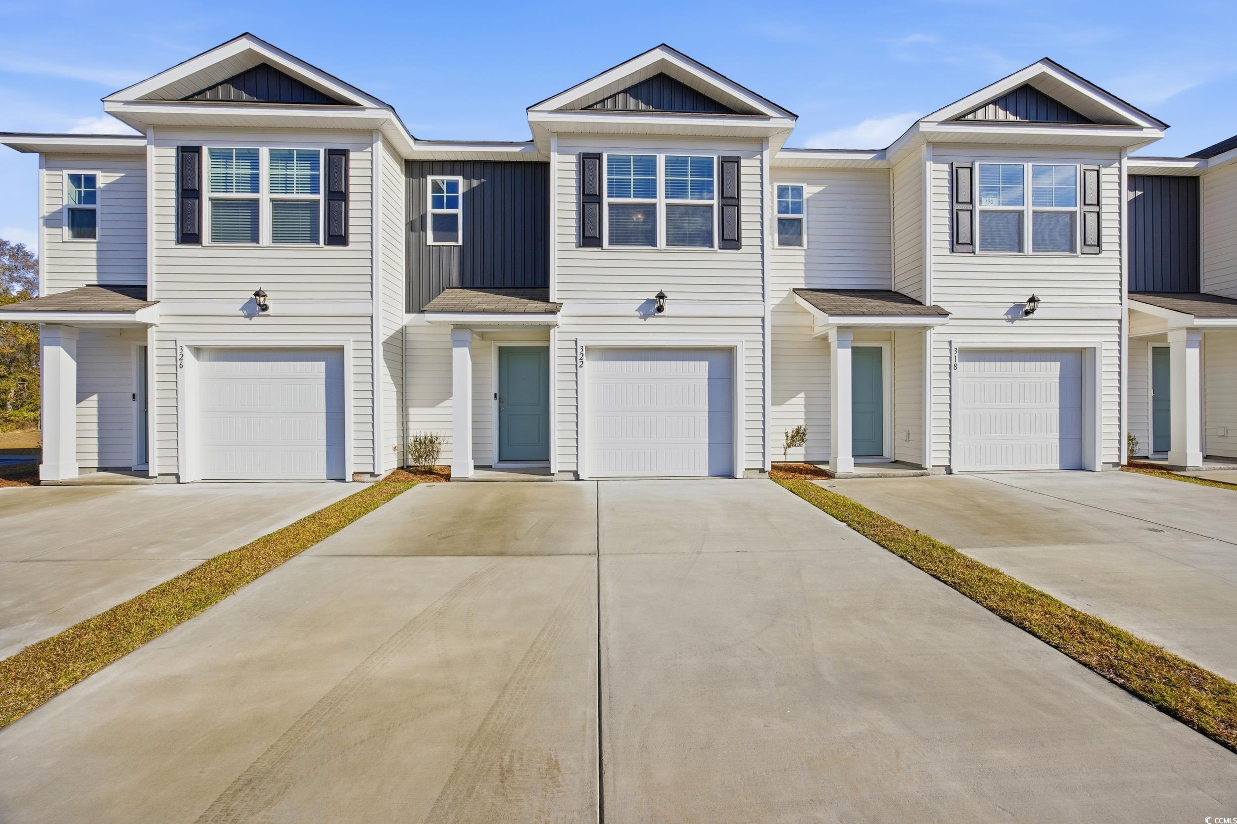View of front facade featuring board and batten siding, driveway, and a garage