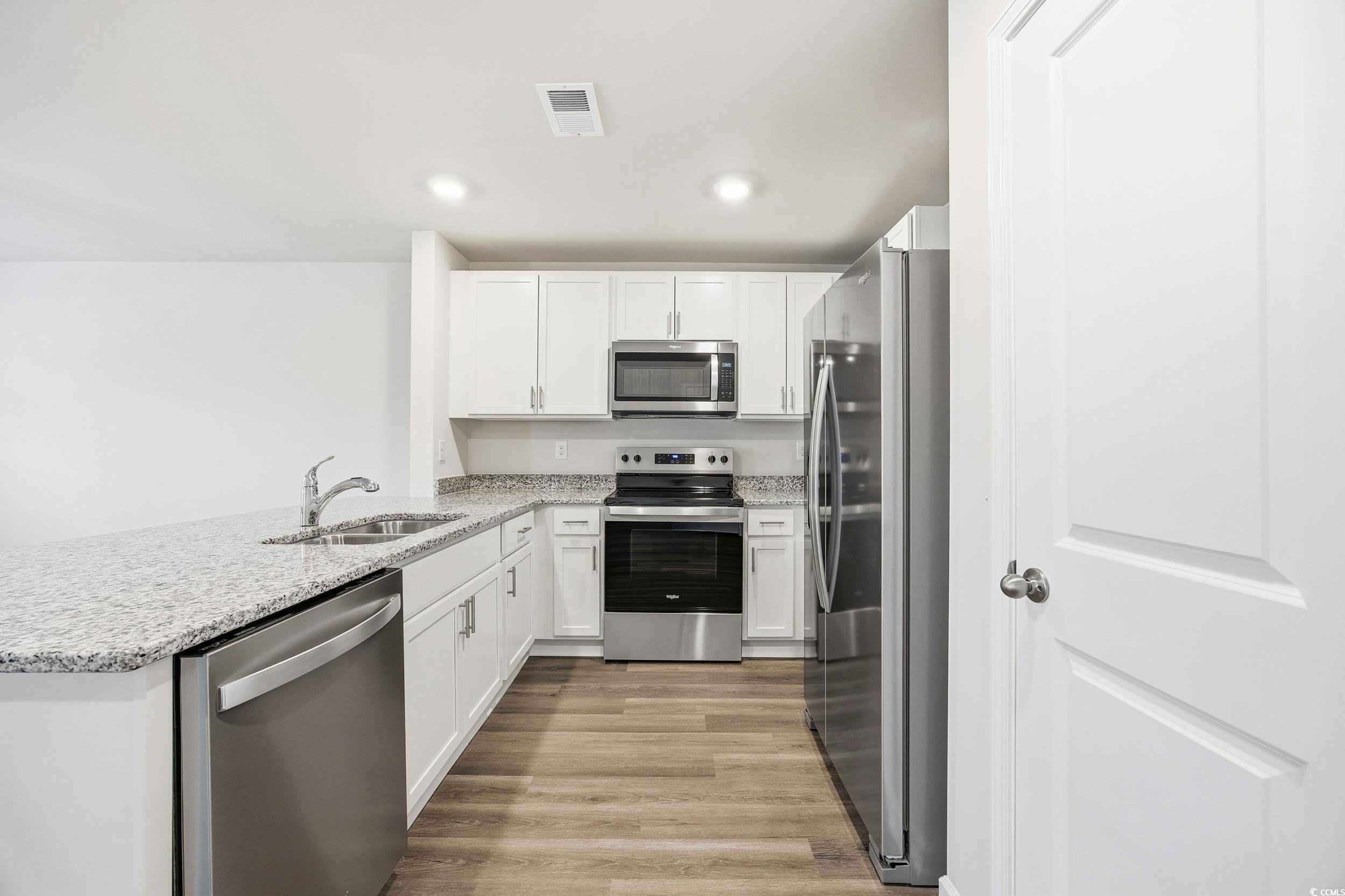 322 Honeystone Street Conway, SC 29526 - Photo 7 of 30 Kitchen featuring appliances with stainless steel finishes, white cabinetry, light stone countertops, light wood-style floors, and recessed lighting
