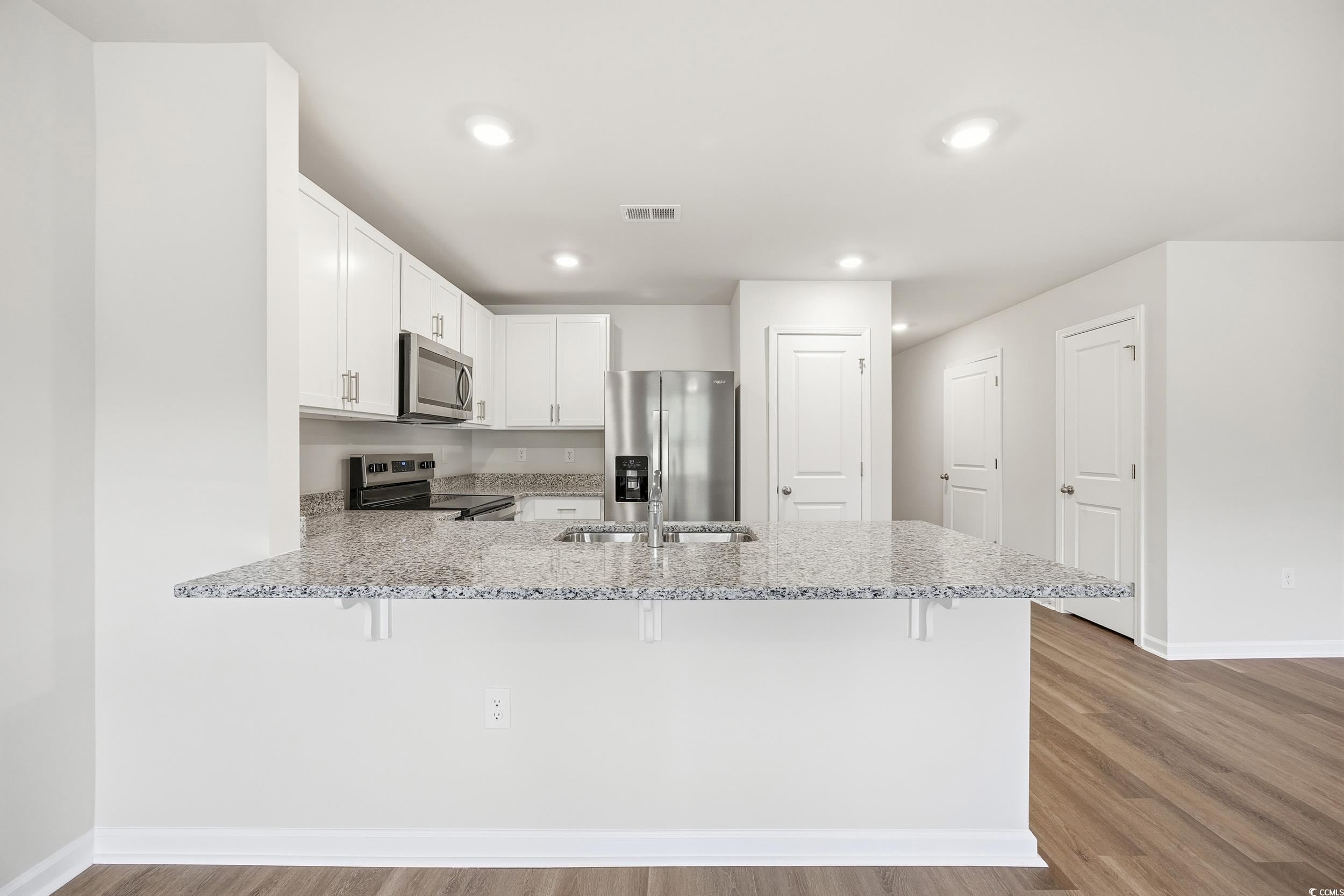 322 Honeystone Street Conway, SC 29526 - Photo 8 of 30 Kitchen with white cabinetry, a peninsula, light stone countertops, a breakfast bar, and stainless steel appliances