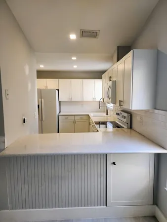 a view of an empty room with wooden floor and window