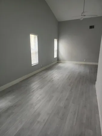 an empty room with wooden floor and windows
