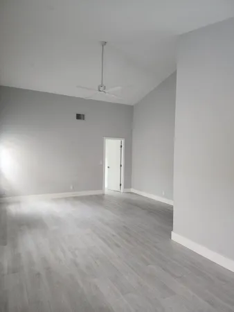 an empty room with windows and fan