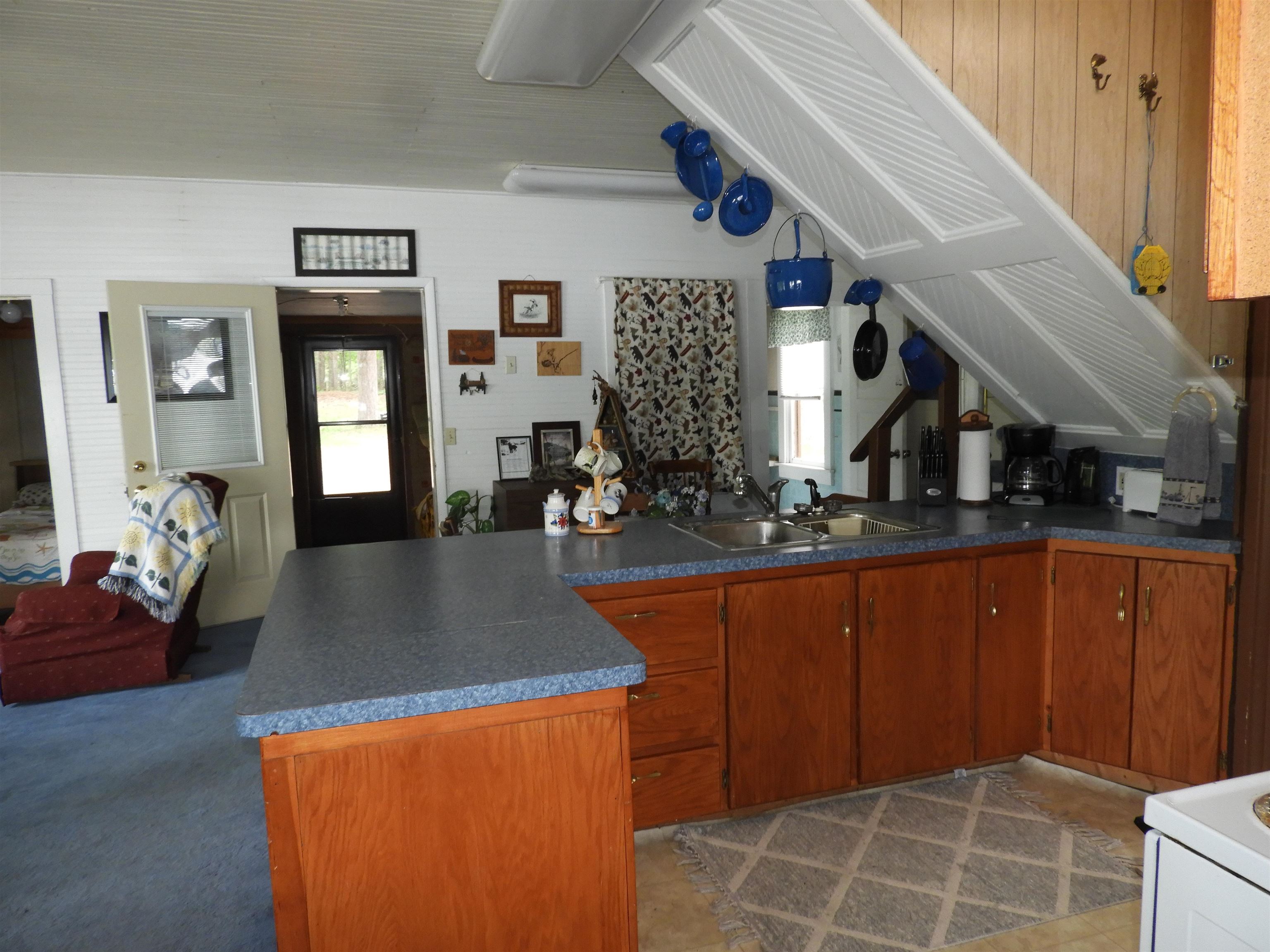 Kitchen featuring a sink, brown cabinetry, dark countertops, and a peninsula