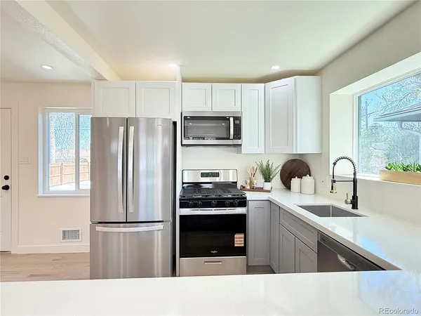 a kitchen with a refrigerator a sink a stove a microwave and cabinets