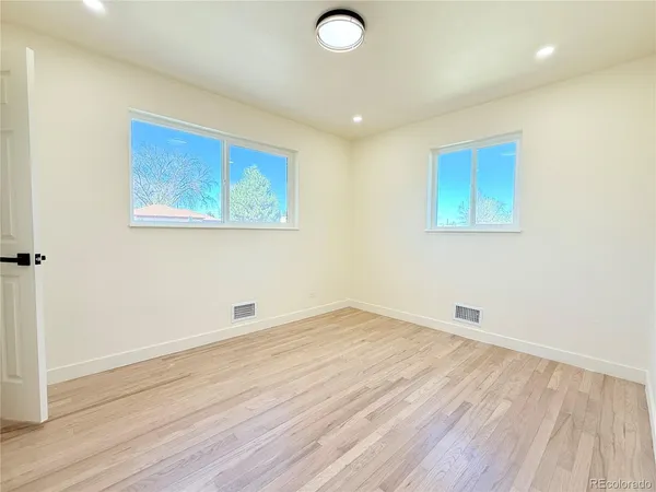 an empty room with wooden floor and windows
