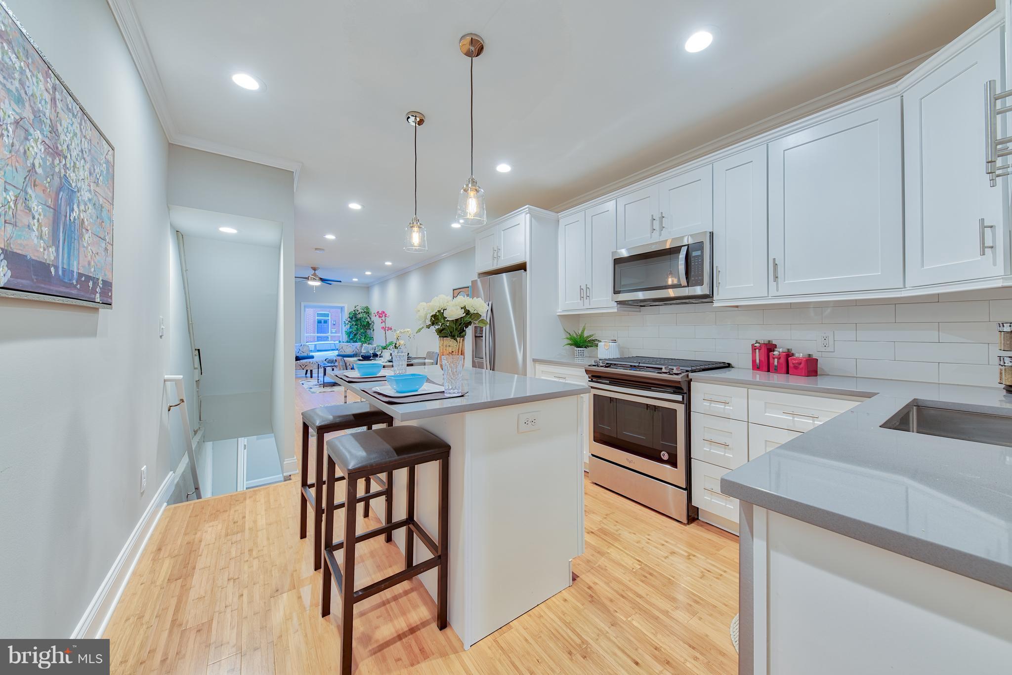 115 North Decker Avenue Baltimore, MD 21224 - Photo 11 of 30 a kitchen with stainless steel appliances granite countertop a stove top oven a sink dishwasher a dining table and chairs with wooden floor