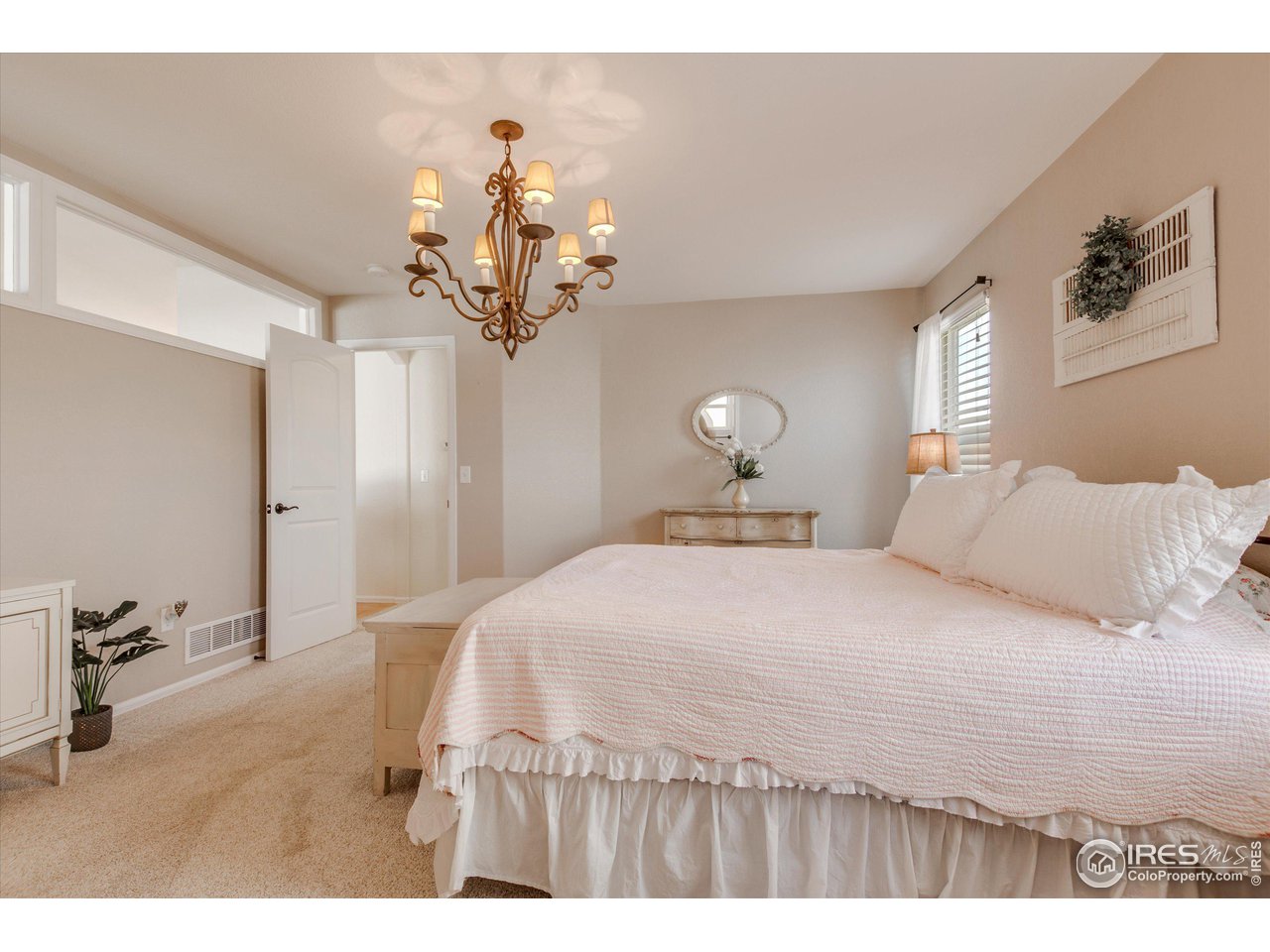 5771 Mountain Shadows Boulevard Firestone, CO 80504 - Photo 17 of 40 a bedroom with a large bed and a chandelier