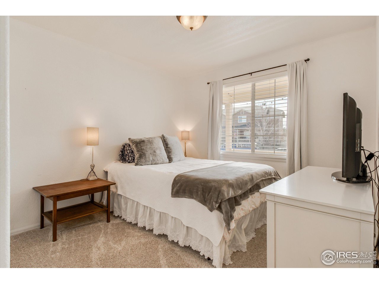 5771 Mountain Shadows Boulevard Firestone, CO 80504 - Photo 22 of 40 a bedroom with a bed table and flat screen tv