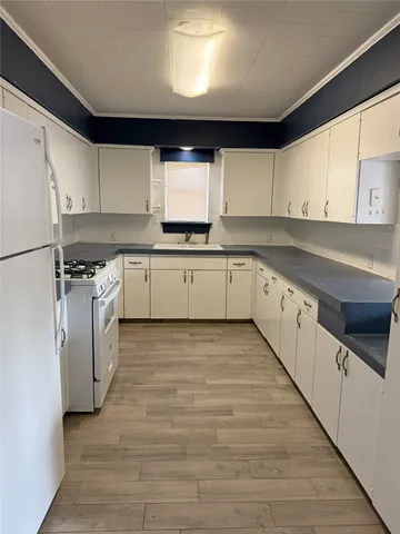 a kitchen with wooden cabinets sink and white appliances